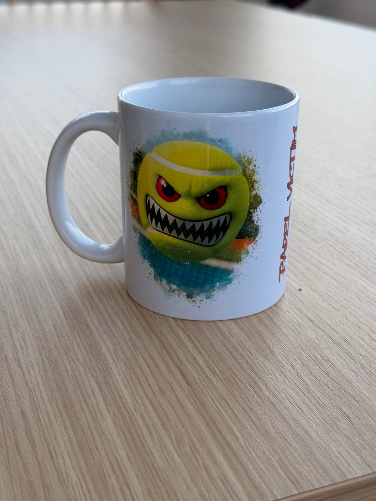 Mug Tomahawk 325 ml, face avec balle jaune aux yeux rouges et aux dents acérées.